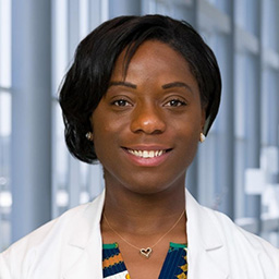 Dr. Stefany Anderson wearing a patterned shirt and a white lab coat standing in the Clements University Hospital lobby