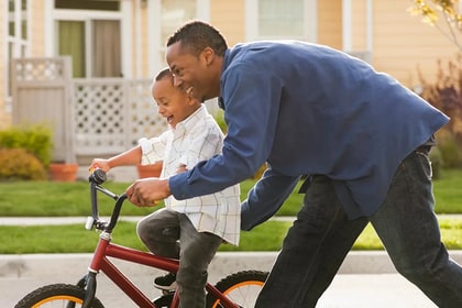 father pushing his son on a bike