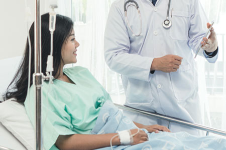 Female patient in hospital bed having a conversation with a doctor
